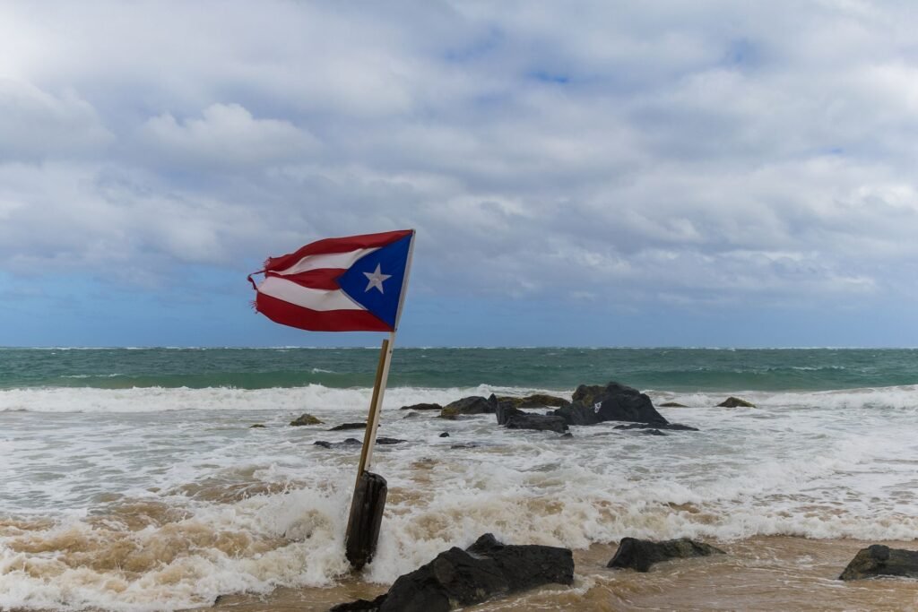 Bandera de Puerto Rico ante el embate del oleaje en una playa. Phil Evenden, Pexels.